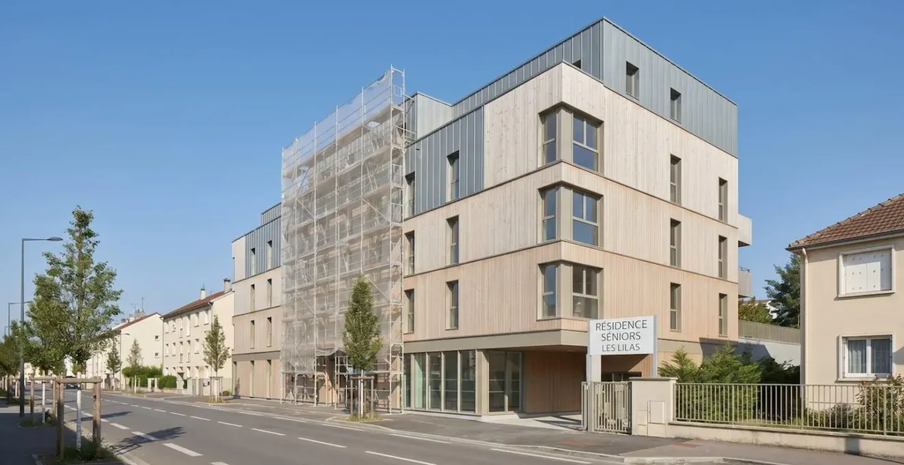 Vue extérieure d'une résidence senior en cours de ravalement de façade, ciel dégagé, échafaudages discrets